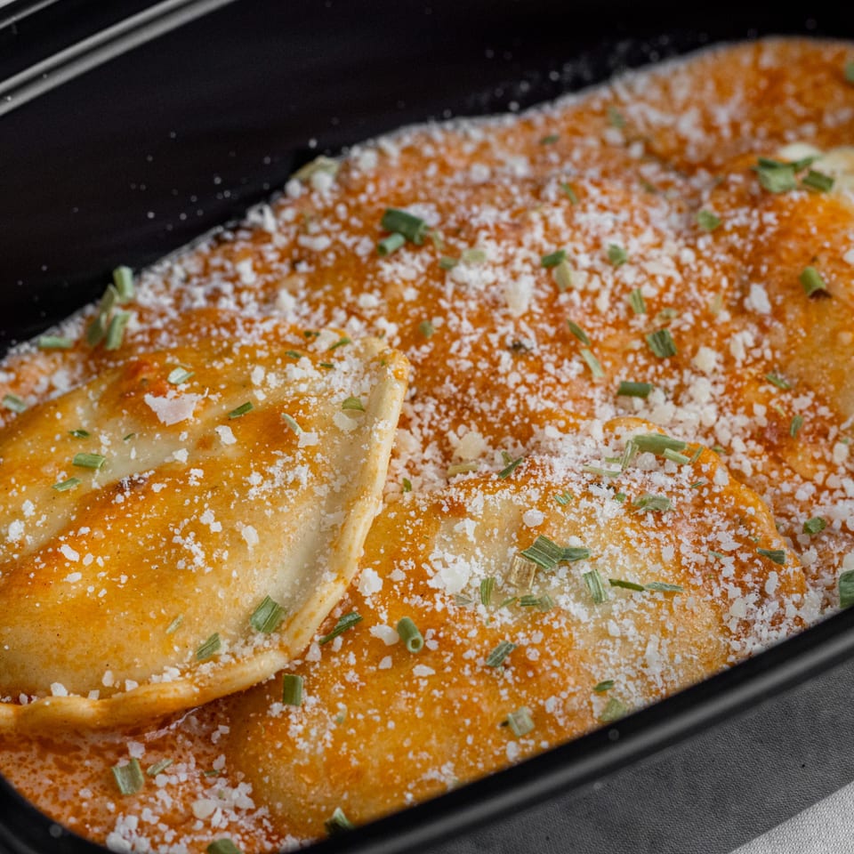 Corbos Pasta and Pizza House's ravioli in a creamy sauce, topped with grated cheese and chives.