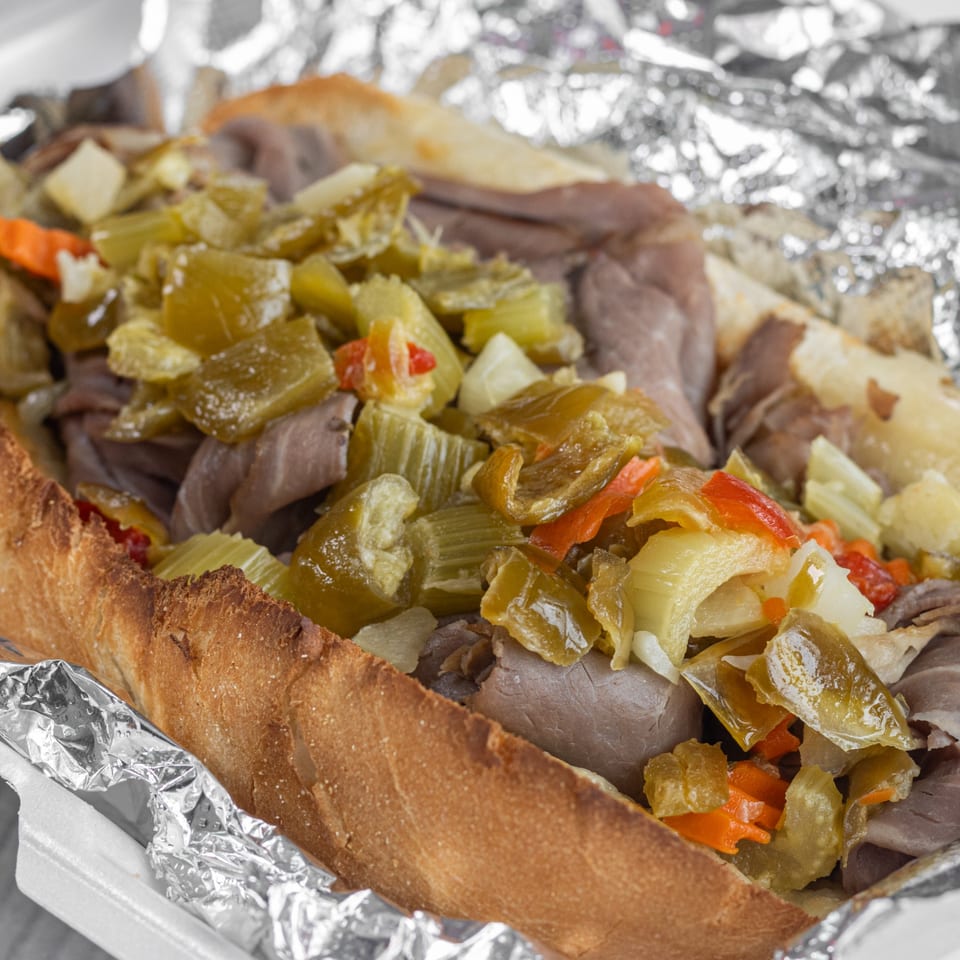 Corbos Pasta and Pizza House Italian beef sandwich with giardiniera in a foil-lined container.