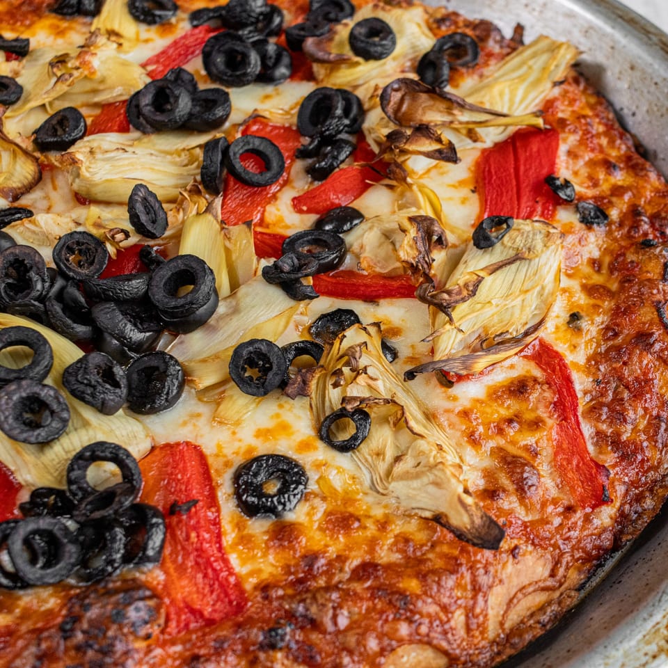 Corbos Pasta and Pizza House pizza with black olives, red peppers, and artichoke hearts.